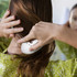 A hair detangler in use, featuring a curved white design, against a backdrop of a person with long, brown hair.