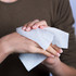 A hand holding a small, white compressed towel, showcasing its texture and design.
