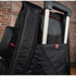A black backpack with a trolley handle concealed in a side pocket, featuring a textured design and a logo.
