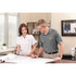 A grey short sleeve polo with a logo, worn by a man, alongside a woman in a white polo, both at a desk.