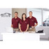 A trio of individuals wearing burgundy short sleeve polo shirts with logos stand at a reception desk.
