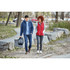 A man in a navy puffer jacket and a woman in a red puffer vest walk on a path, accompanied by a bag.