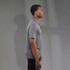Men's polo shirt in grey, featuring a logo. Shown on a model from the side against a neutral background.