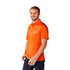 An orange short sleeve performance polo shirt with a logo, worn by a man smiling.