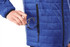 A blue insulated puffer jacket with a hand placing a tool into a zipped pocket. The jacket features a logo.