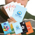 A person holding a fan of playing cards featuring various designs and colors, including logos and promotional cards.