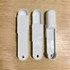 Three white measuring scoops arranged on a wooden surface, featuring different designs and shapes.