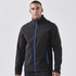 A man wearing a black softshell jacket with blue accents and zippered pockets, featuring a logo.
