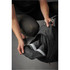 A black duffle bag being opened, revealing a pair of shoes inside. The bag has a logo on it.