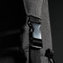 A close-up of a black duffle bag strap featuring a plastic clip fastener and textured fabric.