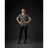 A woman poses in a fitted, multicoloured grey Pacifica tee, paired with black leggings and shoes against a dark background.