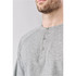 A grey men's henley shirt featuring a button-up neckline, with contrasting raglan sleeves and a subtle logo.