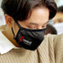 A black reusable cotton face mask with a logo, worn by a person.