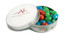 A tin containing mini jelly beans in red, green, and blue colours, with a branded white lid.