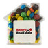 A clear acrylic house filled with colourful M&Ms in various shades of blue, green, red, yellow, and brown.