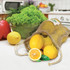 A jute net produce bag filled with lemons, accompanied by a cut lemon and a bowl of greens.