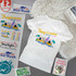 A white t-shirt featuring a colourful design with beach elements and logos, arranged on a flat surface.