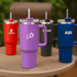 A drink bottle with a purple body and a transparent lid, featuring a straw, alongside red, black, and blue bottles, each with a logo.