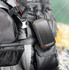A solar-powered wireless power bank in black with orange accents, attached to a backpack.