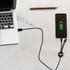 A round-shaped, long light-up charging cable connects a laptop to a smartphone on a marble surface.