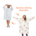 A reversible, wearable blanket in white and patterned designs, featuring a hood and pocket.
