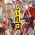 A bright yellow cheerstick in the shape of a sword held up in a cheering crowd, featuring a logo.