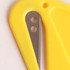 A yellow letter opener featuring a metal blade and a plastic handle, with a small hole at the top for hanging.