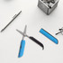 Multifunctional scissors with a blue handle, alongside a silver pen, a black ruler, and glasses on a light surface.