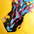A yellow soccer ball featuring a vibrant geometric pattern in blue, pink, and black, with a logo present.