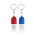 A red and white pill capsule keychain alongside a blue and white pill capsule keychain, both with logos.