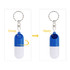 A blue and white pill capsule keychain with a round opening mechanism and a metallic keyring attachment.