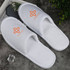 White hotel slippers with a logo on the upper side, featuring a soft texture and a simple design.