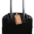A cork luggage tag in a natural tan colour attached to black suitcase handles. The tag features a logo.