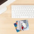 A 3-in-1 microfibre cleaning mouse pad in blue with a logo, alongside a computer keyboard and credit cards on a desk.