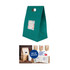 A teal die cut handle bag with a flap, featuring a decorative label and a logo on the front.
