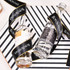 A pair of glass bottles wrapped in a black ribbon with gold edges and a branding logo. The background features a striped design.