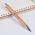 A bamboo pen with a silver clip rests on a lined notebook, featuring a logo on its barrel.