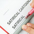 A writing pen with a pink barrel and a transparent grip, resting on a page with bold text. The pen has a logo.