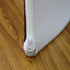 A white fabric display with a visible zipper, set against a wooden surface.