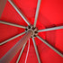 A red patio umbrella with a sturdy metal frame, viewed from underneath, showcasing its structure.