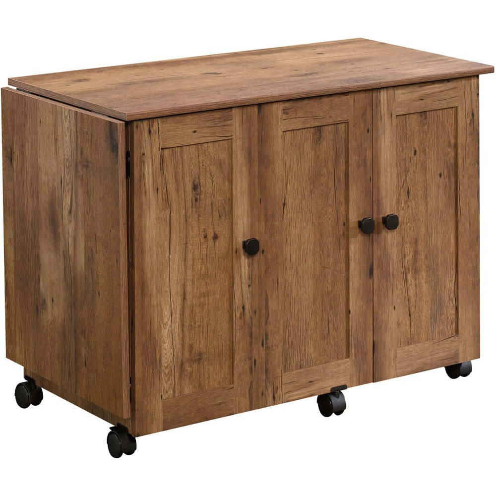 Take your crafting to the next level with help from the Sauder Select Sewing And Craft Table. A drop leaf table top offers additional workspace for bigger projects. Utilize adjustable shelves to organize all of your sewing and crafting accessories with ease.  Made from engineered wood.  Drop leaf workspace.  2 adjustable shelves.  2 storage bins.  1 hidden sewing machine shelf.  Roll-open door.  Easy-roll casters.  This product is heavy and/or oversized and may need more than one person to handle.