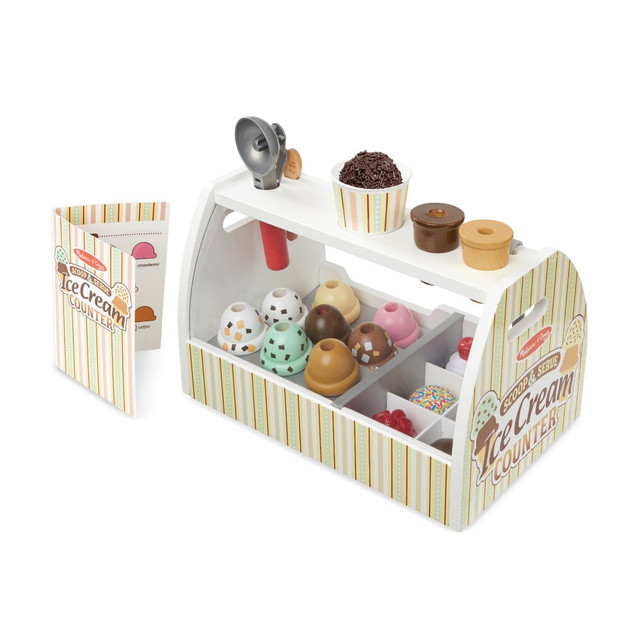 Serve up delicious fun with this 28-piece pretend play ice cream counter! The sturdy wooden counter includes eight scoops of different-flavored ice cream, six toppings, cones, a cup, and more. Use the ice cream scooper to stack scoops, serve customers using the reusable menu card, and even make transactions with play money.  28-piece wooden ice cream play set  Includes wooden ice cream counter, scoops, toppings, cones, cup, scooper, tongs, and wooden spoon  Scoops stack on cone or in cup, with toppings fitting snugly over the scoop  Realistic scooper lifts and releases scoops  Encourages imaginative play, counting, and role-playing  Comes with six $1 bills for play transactions  For ages 3+ years