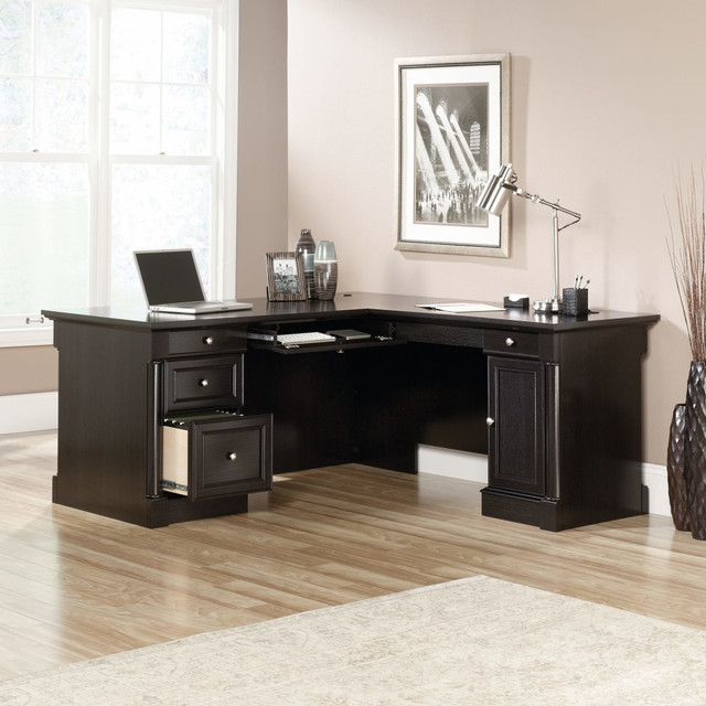 An efficient work area can help ensure that everything you need is within easy reach during a busy day. This versatile Sauder L-shaped desk give you the space you need to keep office supplies handy inside the storage drawer and organize your files in the full-extension file drawer. The side door of this Palladia Collection desk reveals a storage area with an adjustable shelf that can be uses to hold extra paper or even your CPU.  Engineered wood construction for durability.  Flip-down keyboard/mouse panel easily tucks away.  3 storage drawers and 1 file drawer holds office essentials and documents.  Cabinet with adjustable shelf can be used to conceal a CPU.  L-shaped desk comes in a wind oak finish.  This product is heavy and/or oversized and may need more than one person to handle.