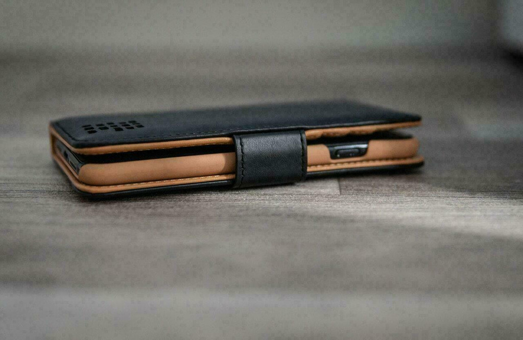 Folded Royale wallet case with wrist strap on surface