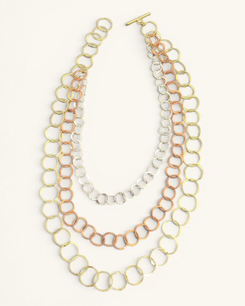 Three-strand mixed metal chain necklace laid flat on white background with all three circle-link strands and toggle bar clasp visible
