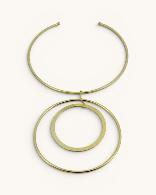 Hand-forged brass collar necklace with two concentric ring pendants, flat lay on white background