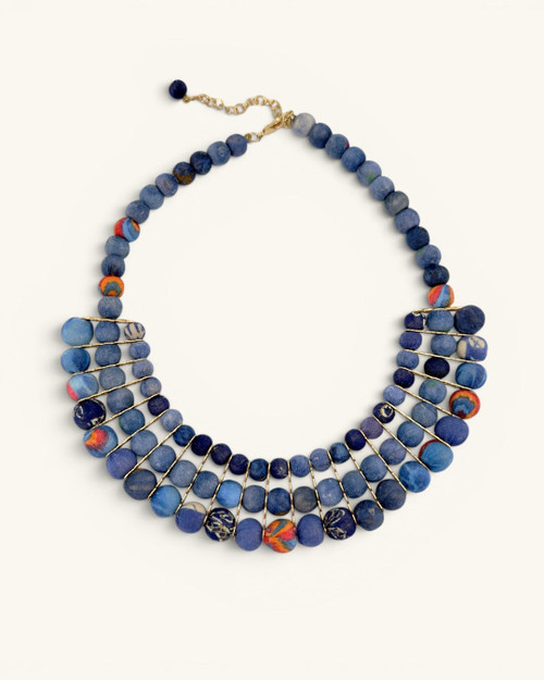 Blue textile-wrapped bead layered necklace flat lay, front view showing four-row bib design with gold wire detail