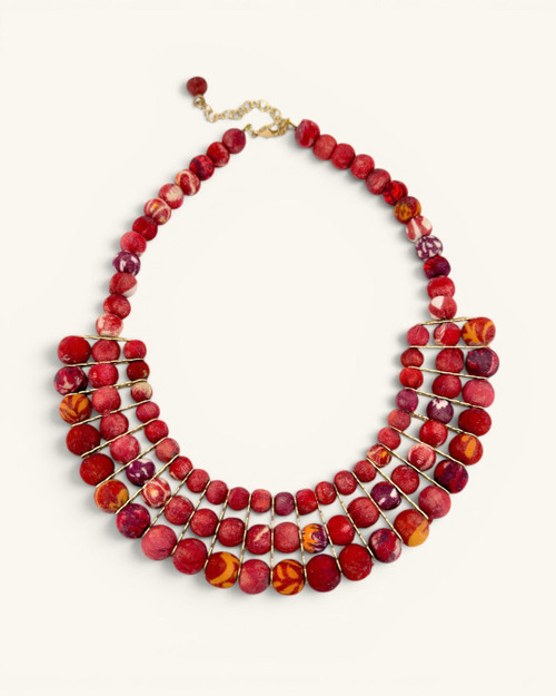 Red textile-wrapped bead layered bib necklace flat lay, four rows of mixed red beads with gold wire connectors and clasp