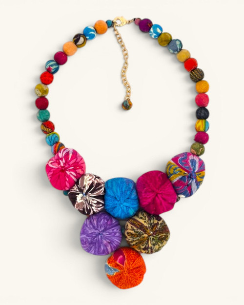 Kantha recycled textile layered bead necklace laid flat, showing multicolor fabric medallion pendant and beaded strand with gold clasp