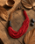 Red horn and coconut bead asymmetric necklace arranged in flatlay with tropical leaves